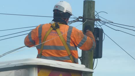 Telecom-technician-working-repairing-telephone-pole-power-cable-in-boom-crane-basket-closeup