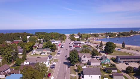 Forward-aerial-along-street-by-Lake-Superior-in-Grand-Marais,-Michigan