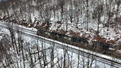 Norfolk-Southern-Railway-diesel-engine-train-locomotive-travels-through-snowy-mountain-forest-scene-in-winter