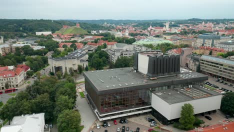 AERIAL:-Wide-Shot-of-Lithuanian-National-Opera-and-Ballet-Theatre-in-Vilnius-on-a-Summer-Day-with-Gediminas-Hill-In-Background