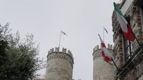 Beautiful-castle-towers-with-waving-flags-of-Italy,-handheld-slow-motion-shot