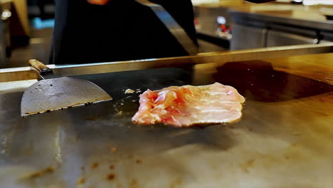 Ein-Japanischer-Koch-Bereitet-Gebratenes,-Geschnittenes-Schweinefleisch-Auf-Einem-Kochherd-Zu,-Um-Die-Gäste-In-Einem-Ambiente-Restaurant-Zu-Speisen