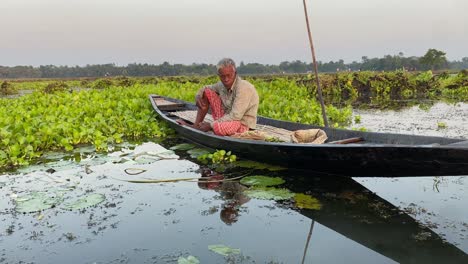 Una-Persona-Pescando-Con-El-Barco-Tradicional-Durante-La-Luz-De-La-Mañana-En-Los-Remansos-De-Kolkata,-India-En-Bortirbil