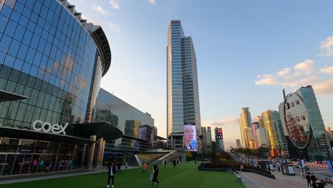 Zeitraffer---Menschen,-Die-Bei-Sonnenuntergang-In-Seoul,-Südkorea,-In-Der-Nähe-Des-Coex-Einkaufszentrums,-Des-Asem-Turms-Und-Des-HDC-Youngchang-Gebäudes-Spazieren-Gehen