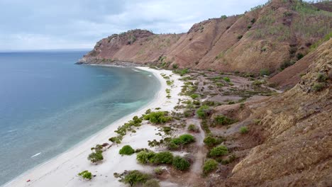 Luftdrohnenflug-über-Einen-Abgelegenen,-Abgelegenen-Weißen-Sandstrand,-Küstenblicke-Und-Hügel-Der-Trockenzeit-In-Dili,-Timor-Leste