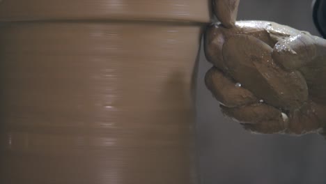 Extreme-close-up-of-potter-using-scrapper-to-smoothen-and-carve-fine-edges-of-clay-vessel