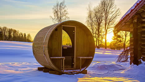 Thermowood-Barrel-Sauna-Next-To-Wooden-Cabin-With-Bright-Sunset-In-Background