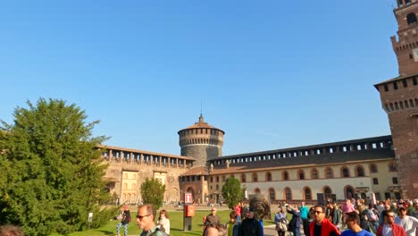 Panning-view-of-people-in-main-courtyard-of-Sforza-Castle-or-Castello-Sforzesco-in-Milan,-Italy