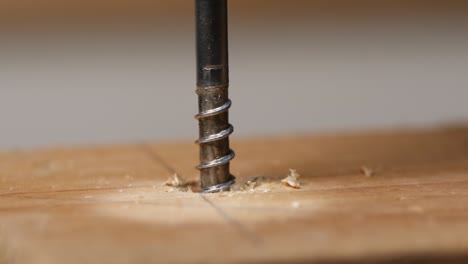 Slow-motion-cordless-screwdriver-screws-in-a-bolt-in-wood,-epic-macro-shot