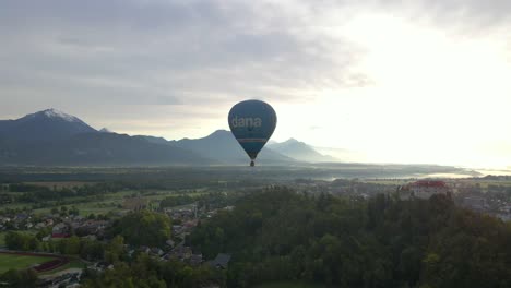 Hot-air-balloon-trip-during-bright-sunrise-with-Bled-Castle-on-hill,-aerial