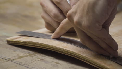 Close-up-of-experienced-male-hands-taking-measurements-on-a-rounded-wooden-board