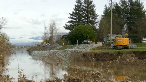 A-team-of-construction-workers-hard-at-work-reinforcing-and-raising-the-banks-of-a-dike-as-a-precaution-ahead-of-the-expected-heavy-rains-in-Abbotsford,-British-Columbia,-Canada