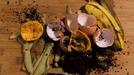 Compost-material-laid-out-on-a-cutting-board,-eggshells,-coffee-grounds,-banana-peel