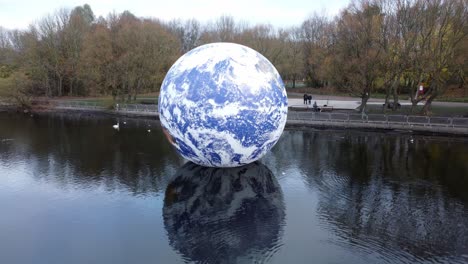 Luke-Jarram-floating-planet-earth-art-exhibit-aerial-view-at-Pennington-flash-lake-fast-descend