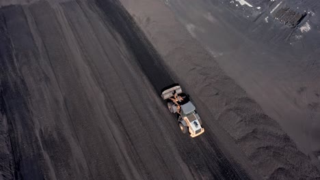 Aerial-tracking-shot-of-Digger-working-on-coal-mining-field-and-transporting-coal