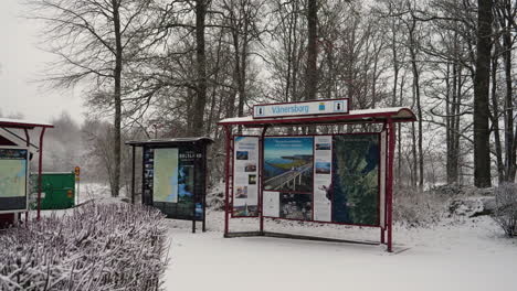 Vänersborg-tourist-notice-board-in-winter-forest-while-snow-falls