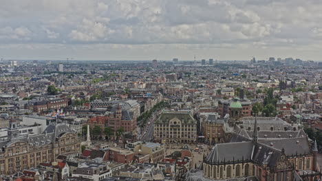 Amsterdam-Netherlands-Aerial-v9-reverse-flying-away-from-popular-cultural-landmark-dam-square,-capturing-downtown-cityscape-at-binnenstad-neighborhood-with-heritage-dutch-architectures---August-2021