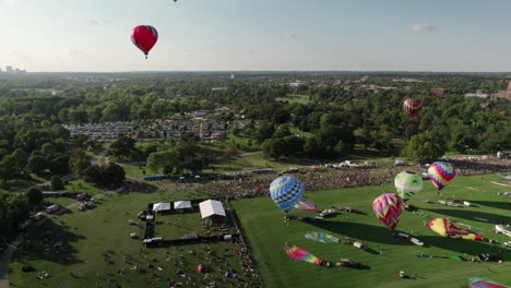 Aerial-rise-of-hot-air-balloons-taking-off-from-Forest-Park,-St