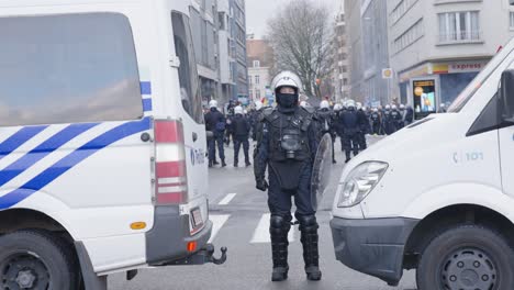 Polizistin-Steht-Während-Des-Protestes-In-Brüssel,-Belgien,-Zwischen-Zwei-Lieferwagen