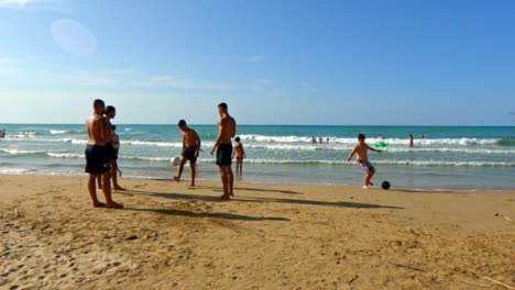 Boys-on-vacations-have-fun-playing-soccer-on-sandy-beach-in-Italy