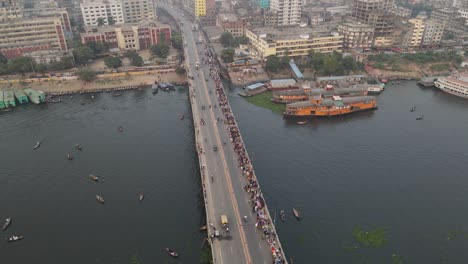 vehicles-traffic-and-hundreds-of-pedestrians-crossing-the-bridge-over-Buriganga-river-in-Dhaka,-Bangladesh