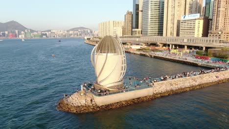 People-walking-on-a-breakwater-with-Central-Wanchai-bypass-east-vent-shaft-in-causeway-bay,-Hong-Kong