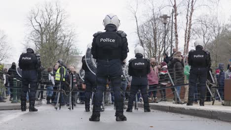 Group-of-social-activists-protesting-in-front-of-armed-riot-police-officers-in-Brussels,-Belgium