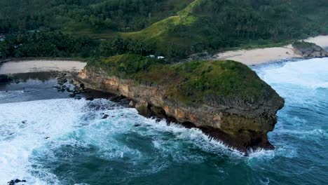 Majestic-rock-hit-by-ocean-wave-on-Kasap-beach,-Java,-Indonesia-aerial-view