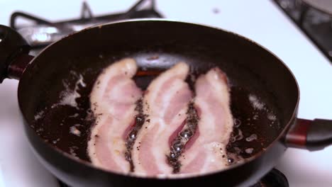 A-time-lapse-or-hyperlapse-of-preparing-bacon-in-a-hot-frying-pan