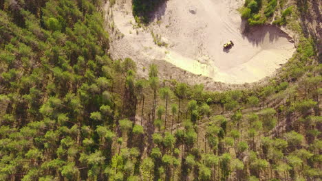 Drone-video-of-an-old-bulldozer-in-a-gravel-pit,-beautiful-coniferous-forest-surroundings