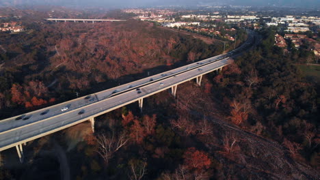 Aerial-fly-over-the-top-of-a-bridge-panning-to-a-suburban-city-at-sunset
