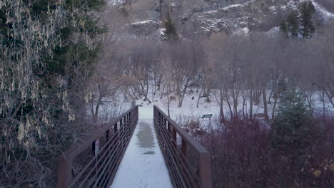 Über-Eine-Schneebedeckte-Brücke-Laufen-Und-Sich-Dann-Umdrehen,-Um-Auf-Den-Rauschenden-Fluss-Unten-Zu-Blicken-–-Standpunkt