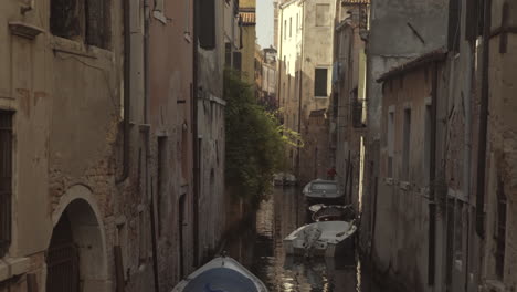Quiet-narrow-street-with-parked-boats-in-Venice,-Italy