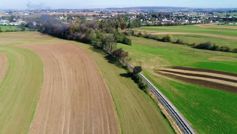 Steam-Passenger-Train-Puffing-Smoke-Along-Amish-Countryside-as-Seen-by-a-Drone