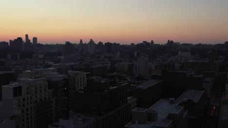 Drone-settles-down-into-cluster-of-buildings-in-New-York-City's-Harlem-neighborhood-at-daybreak-sunrise-golden-hour