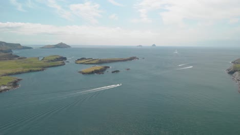 Pleasure-boats-leave-harbor-pass-small-islands-and-head-out-into-vast-open-sea-towards-Blasket-Islands-in-the-Atlantic-Ocean