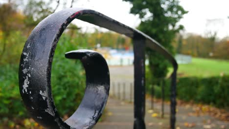 Slow-panning-shot-across-wrought-iron-curved-hand-rail-leading-down-to-park-play-area