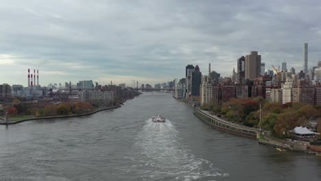 Stationary-drone-shot-looking-down-NYC's-East-River-towards-a-tanker-ship-heading-towards-the-Queensboro-Bridge-between-Manhattan-and-Roosevelt-Island