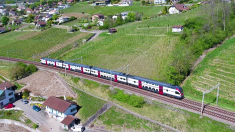 Aerial-of-two-Swiss-trains-crossing-in-Lavaux-vineyard,-shot-follows-one-passing-over-old-viaduct