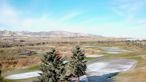 Parallax-shot-of-a-golf-course-in-winter-with-a-light-dusting-of-snow---zooming-in-during-retreating-dolly-move