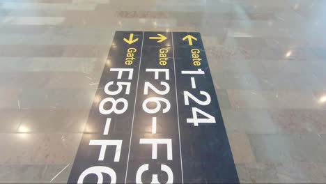 Walking-over-an-airport-floor-sign-showing-different-gates