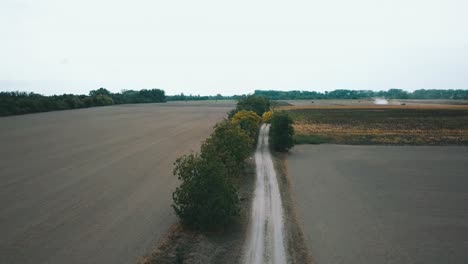 Drone-shot-over-the-field-road-during-harvest