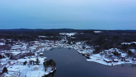 Aerial-footage-flying-high-over-Moosehead-Lake-towards-a-snow-covered-downtown-Greenville-Maine