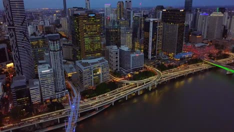Dolly-aerial-view-of-a-modern-city-center-with-highway-along-riverside-at-night