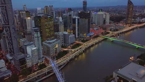 Luftaufnahme-Des-Flussufers-Der-Stadt-Brisbane-Mit-Vorbeifahrender-Autobahn-Bei-Nacht
