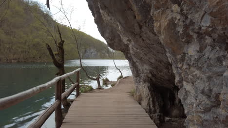 A-man-made-wooden-footpath-between-a-clear-blue-lake-and-mountain-cliff-side
