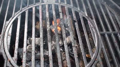 outdoor-grill-bars-closeup-showing-flames-and-smoke-from-burning-charcoal