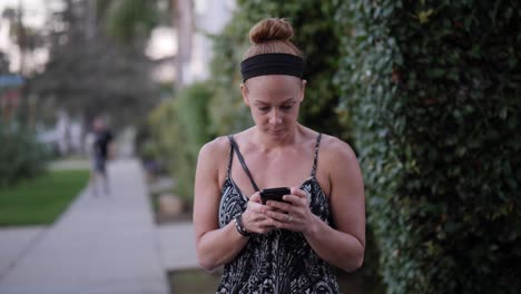 Redhead-Woman-using-her-Smartphone-on-a-Street-Corner