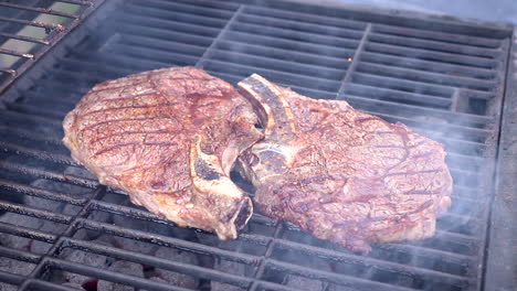 Zoom-out-view-of-big-juicy-steaks-cooking-on-hot-charcoal