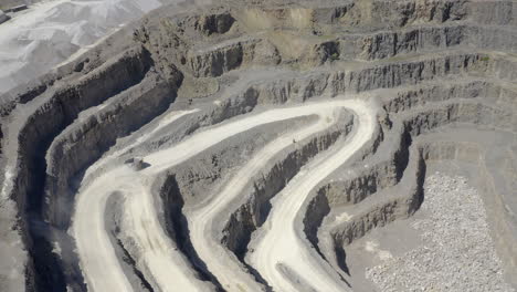 An-aerial-view-of-a-working-asphalt-quarry-showing-a-truck-traveling-down-the-quarry-cut,-Yorkshire,-UK